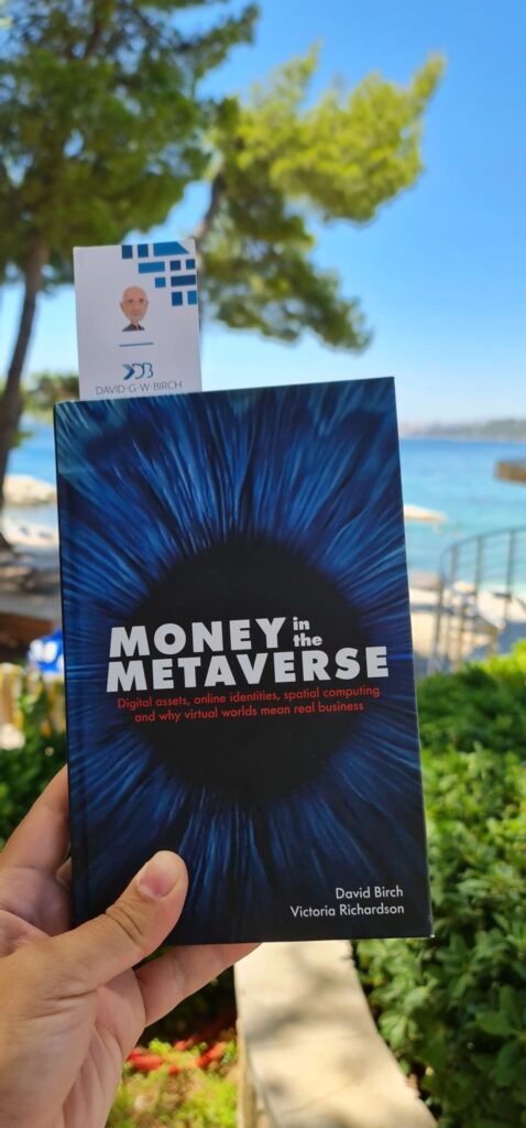 Money In The Metaverse book being held up with beach in the background