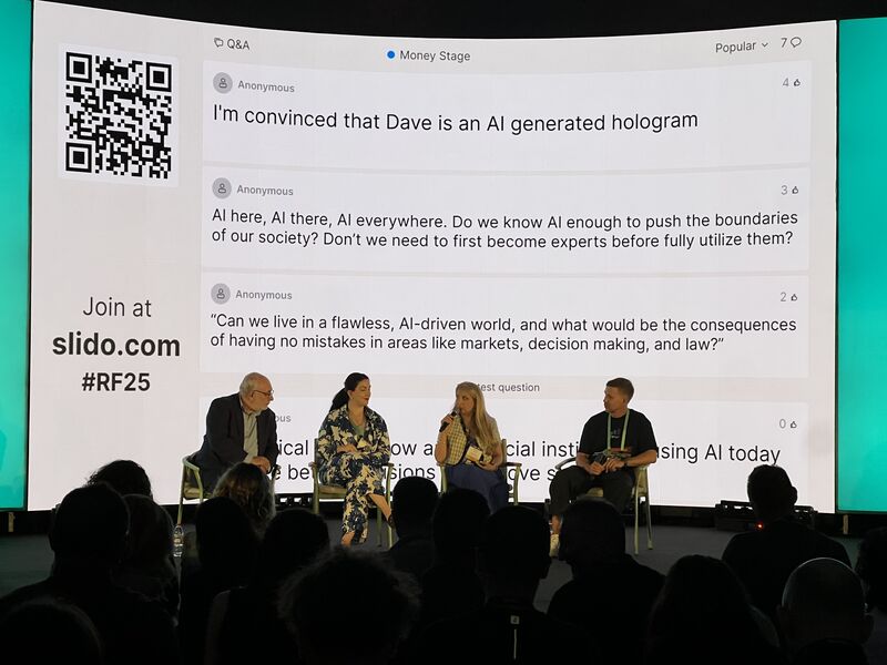 Reflect panel: image of David on stage with fellow panellists and Slido screen in the background displaying questions asked by the audience. KYA KYB KYC