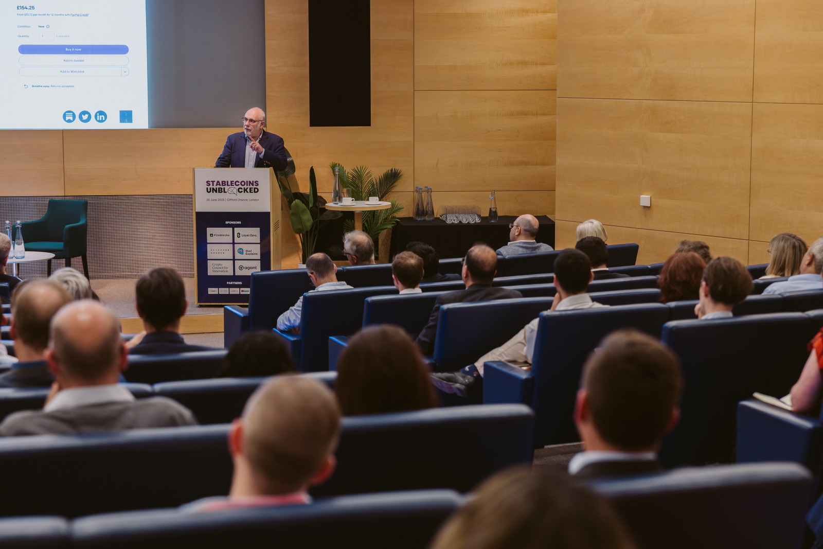 Stablecoins Unblocked Conference: image of David on stage in front of the podium delivering his presentation